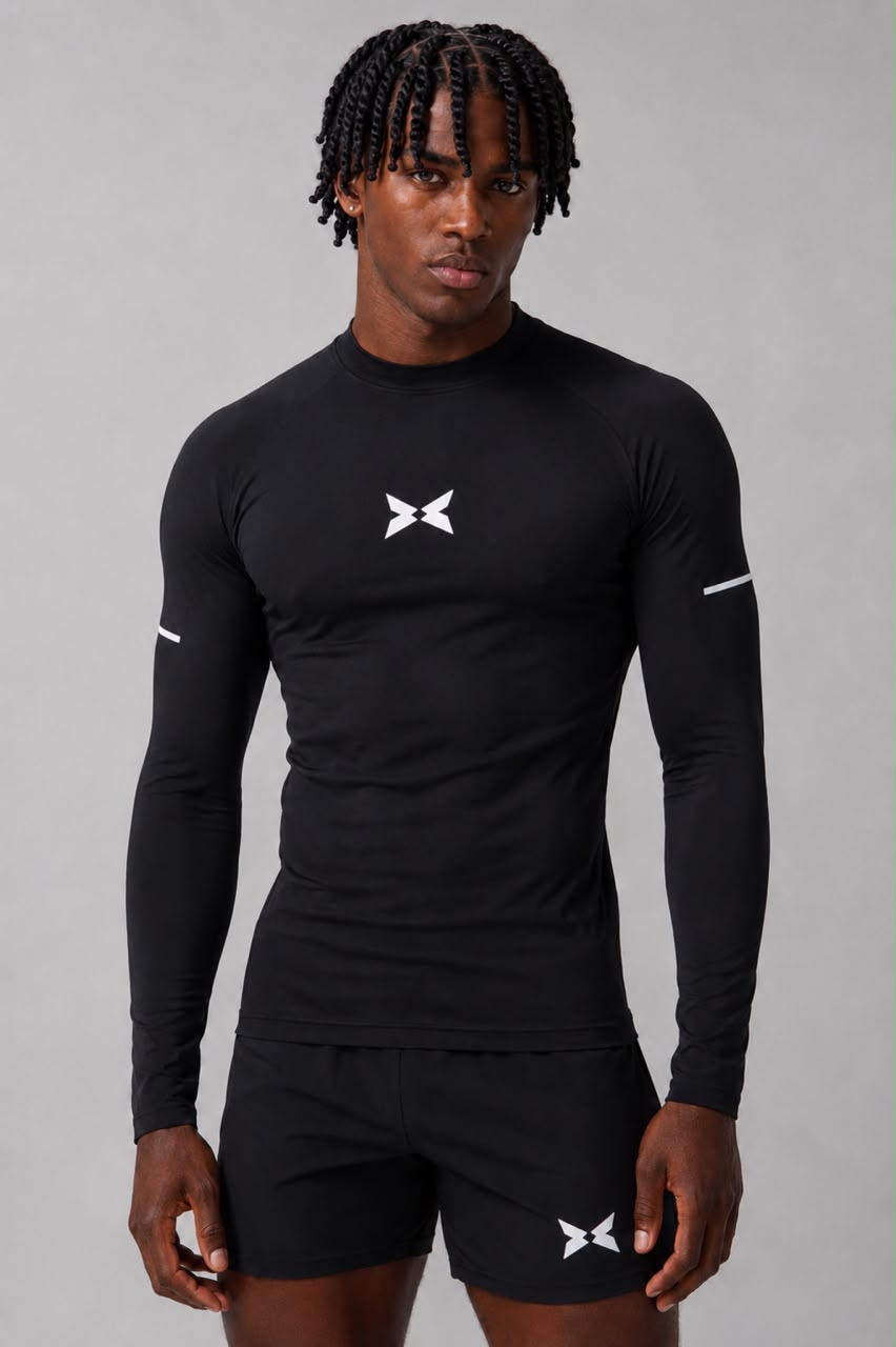 Man wearing a black BRAVO long-sleeve compression top and black shorts against a grey studio background